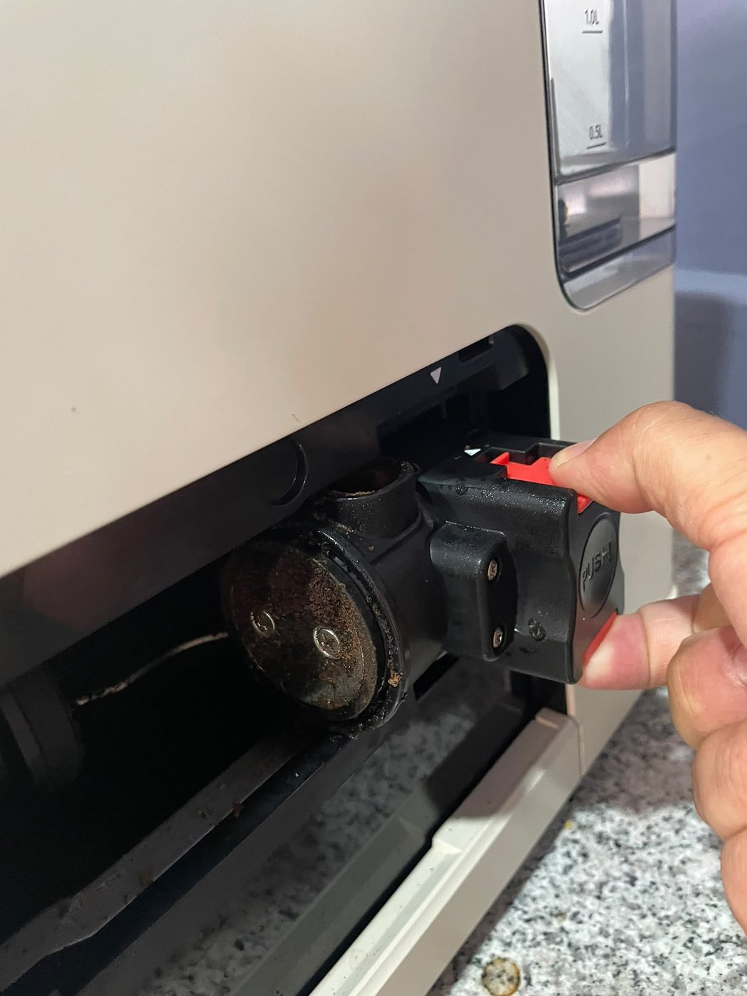 Mão a puxar cuidadosamente o conjunto interior da máquina de café