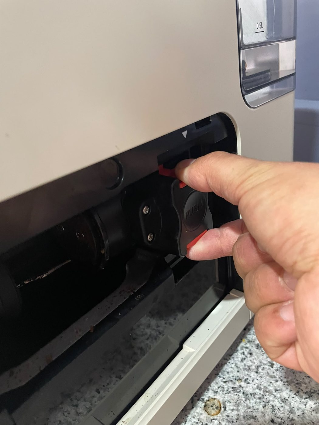 Mão a pressionar as duas patilhas vermelhas da máquina de café