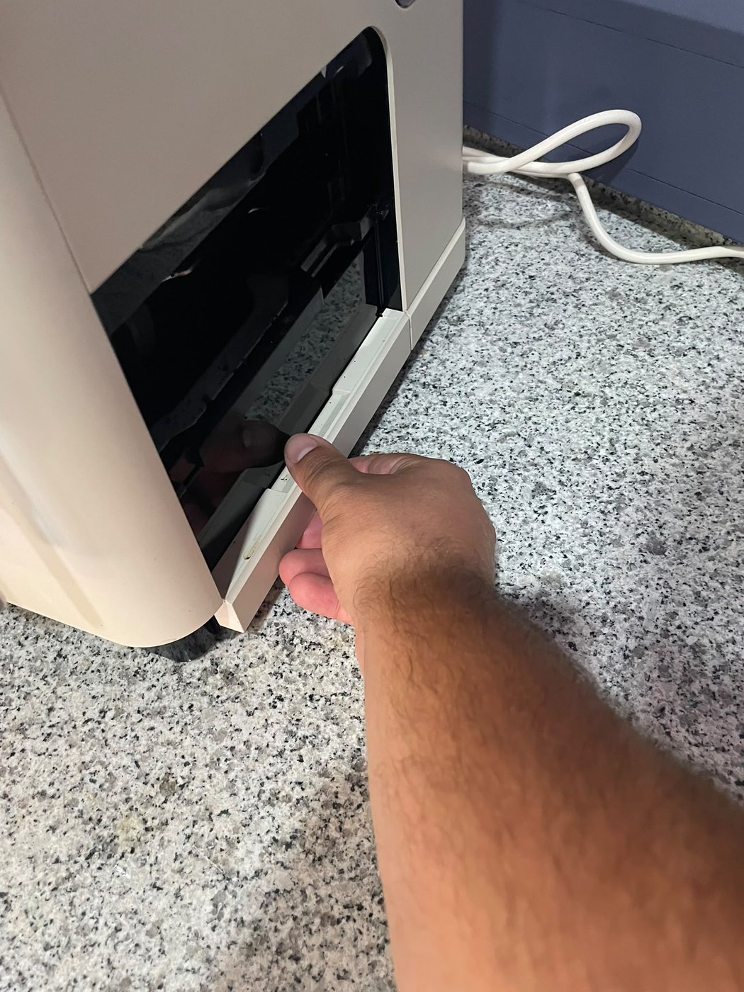 Mão a puxar o tabuleiro inferior da máquina de café